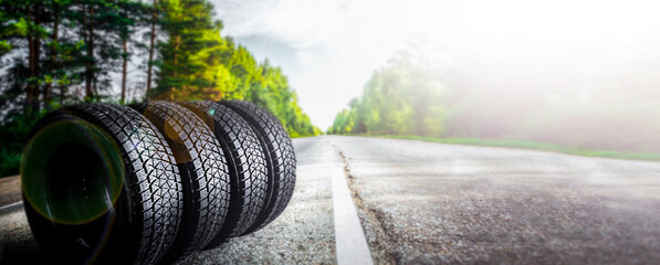 Change a car seasonal tire summer forest road with trees background. Change for winter tire. Banner...