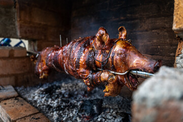 Serbian "Pecenje" pig on a skewer turning over hot ash for an Orthodox event called "slava"