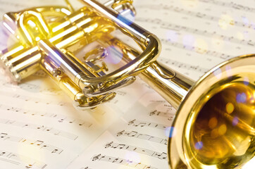 Golden trumpet on sheet music with scenic reflections and lens flare - obrazy, fototapety, plakaty