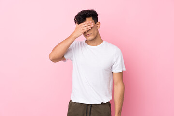 Young Argentinian man over isolated pink background covering eyes by hands