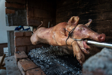 Traditional Serbian "Pecenje" pig on a skewer turning over hot ash for an Orthodox event called "slava"