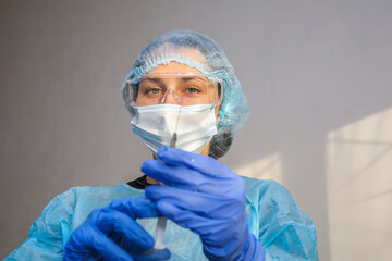 young woman doctor nurse in a protective mask with a syringe in her hand