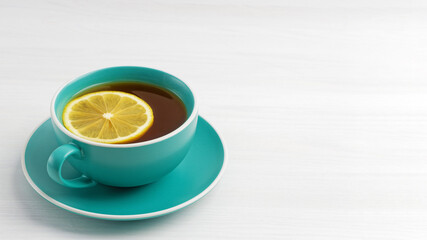 Cup of tea with a slice of lemon on white wooden table. Angle view. Copyspace.