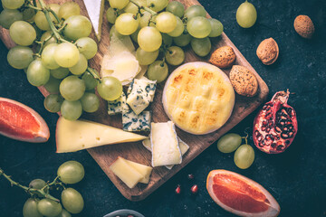 Cheese plate with fatty cheeses and fruits. Bergader Edelpilz, Italian Tomino, Brie, Gouda,...
