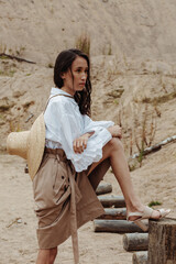 Attractive fashion model with american-indian appearance posing in the sand quarry in a stylish outfit.