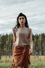 Pretty young woman with native make up and clothing posing dynamically in front of the swamp forest...