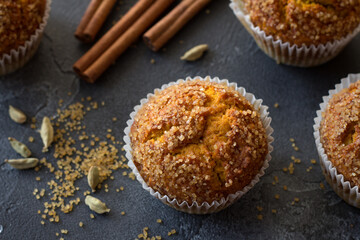 Delicious homemade pumpkin muffins with spicy sugar crust with milk on black textured background, top view