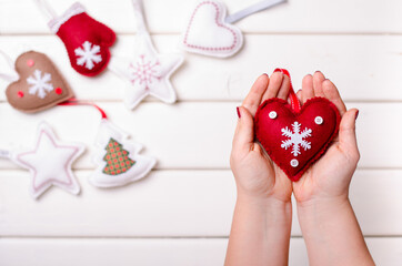 Red felted heart in femaile hand on white wooden background. Xmas and Happy New Year composition