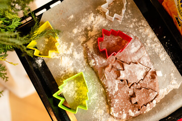 Detailed shot of gingerbread cookies dough and plastic cookies cutter on wooden worktop.