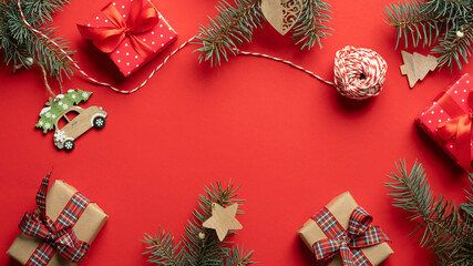 Christmas preparation concept. Flat lay, top view Christmas gifts, pine tree branches, ribbon, wooden decorations on red background. Retro, vintage style.