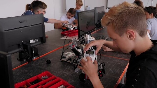 School children teenagers in robotics school makes robot managed from the constructor, robot programming.