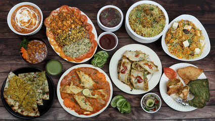 Assorted indian foods chicken biryani,paneer biryani, kulcha, tandoori chicken and spring roll on wooden background. Dishes and appetizers of indian cuisine