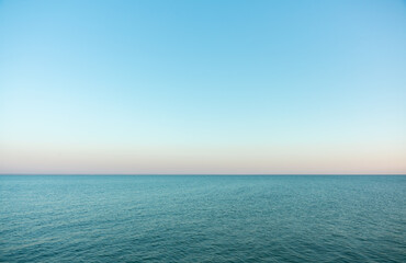 Calm evening sea surface with clear blue sky. Evening seascape. 