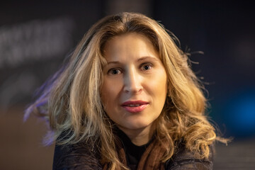 Portrait of a young beautiful blonde woman with gray eyes in the evening in a cafe.