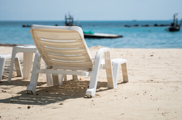 Empty white sunbed on a sand beach with a view on a sea.