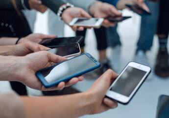 close up. young people with smartphones sitting in a circle