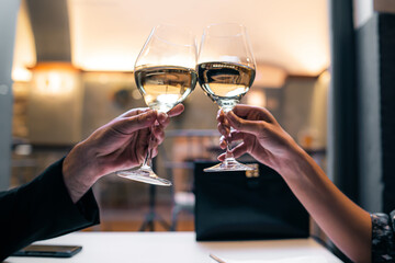 Couple toasting with white wine. closeup on the hands.