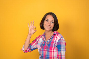 Cute woman shows okey gesture with hand. Smiling female model showing Ok sign. High quality photo
