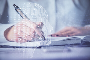 Double exposure of woman's writing hand on background with brain hologram. Concept of brainstorming.