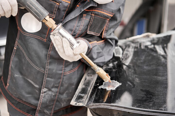 Spotter, a Welding machine for straightening dents on the car body. spot welding of metal. Repair service worker fix damaged car.