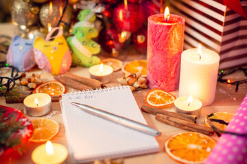 Obraz na płótnie Canvas Notebook, pen and various Christmas decoration and items on the wooden table. Winter holidays, festive atmosphere.