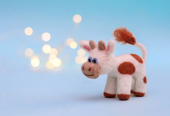 Felt toy bull on a blue background with bokeh