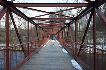 Red iron bridge in Hradek, Beskydy, Silesian region, Czech republic in winter. Architectural shot. Bridge over river Olza / Olse / Alder.