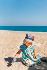 Fototapeta na wymiar Toddler girl playing with sand on beach