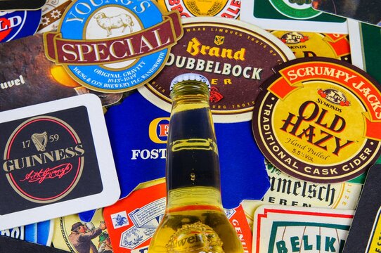 Viersen, Germany - January 8. 2020: Close up of international beer coaster boards with brands from all over the world with yellow bottle