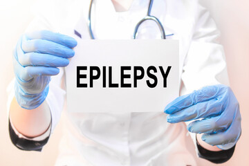 The doctor's blue - gloved hands show the word EPILEPSY - . a gloved hand on a white background....