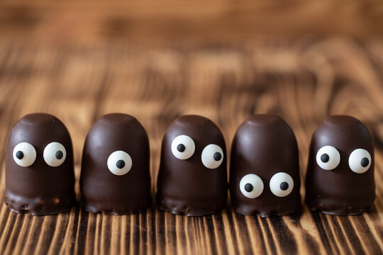 Geist oder Gespenst oder Alien aus Schaumkuss mit Augen aus Zucker auf einem braunen Tisch aus Holz