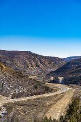 Curve road cutting through tall hills with a clear sky