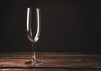 Empty champagne glass on a cozy atmospheric wooden background. Side view, with space for copying. Concept of holiday backgrounds.