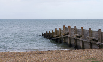 Breakwater leading into sea from shingle beach with space for copy