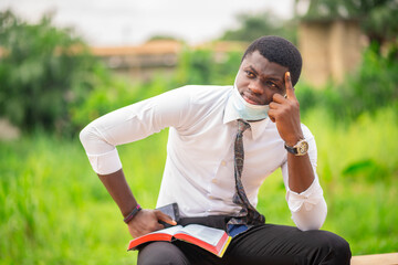 image of African guy, face mask lowered at his chin, with a scripture- bible reading concept