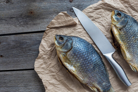 Salted Dry fish vobla with a sharp knife on crumpled craft paper