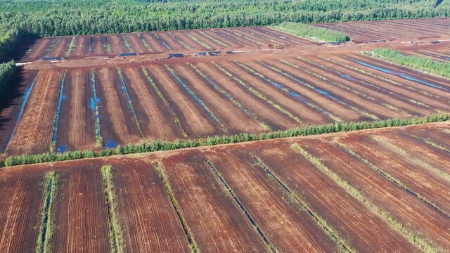 Aerial shot flying over peat harvesting field. Peat extraction