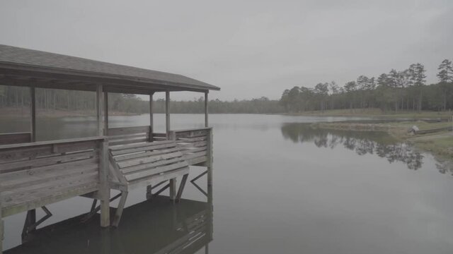Left to right gimbal dolly shot of an isolated wooden pier over a calm lake on a peaceful morning.
