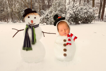 Baby and real snowman posing together in a winter scene