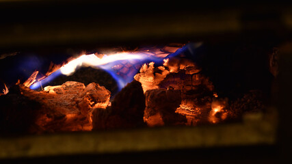 Feuer im Kamin mit brennendem Holz, Flammen und Glut, schwarz, orange, blaue Flamme	
