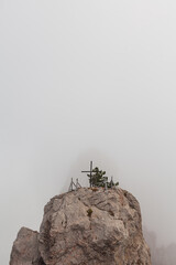Cross on top of a mountain in the fog