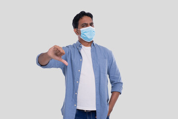 Indian Man Wearing Medical Mask Showing Thumb Down Isolated. Man In Blue Shirt with Medical Mask. Health, Virus, Medical Concept