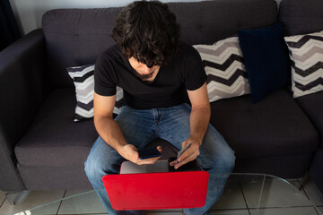 top view of a man shopping online on a laptop and holding a credit card