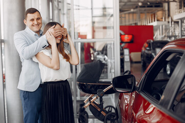 Family in a car salon. Woman buying the car. Little boy with a parents