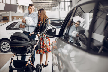 Family in a car salon. Woman buying the car. Little boy with a parents