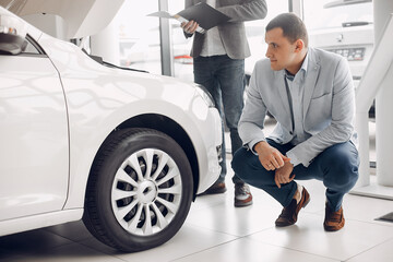 Man buying the car. Businessman in a car salon. Assistant with a client