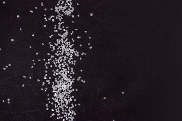 Spilled white sea salt on a black background. clear crystalline pebbles on a black background