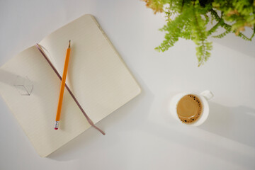 Top view of coffee cup and notebook on a white desk