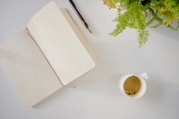 Top view of coffee cup and notebook on a white desk