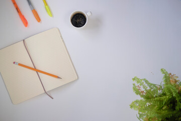 Top view of coffee cup and notebook on a white desk